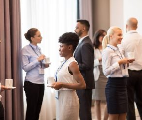 business and education concept - international group of people with conference badges drinking coffee